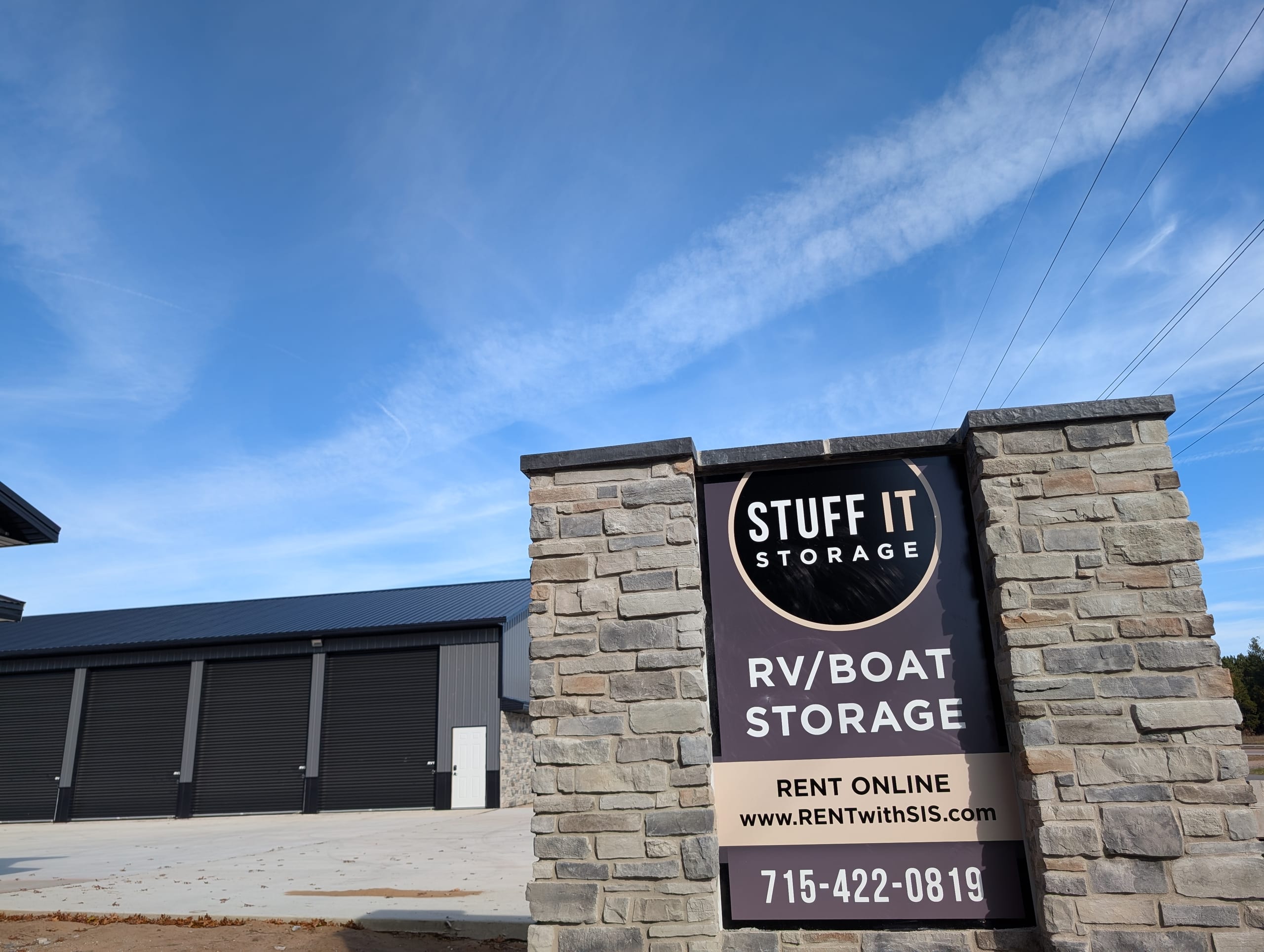 New Rome RV and boat storage building with charcoal roll-up doors beside a stone Stuff it Storage sign